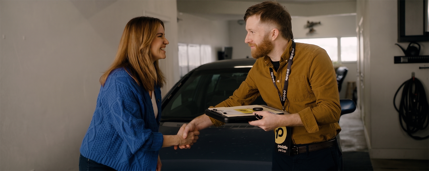 Peddle partner shaking hands with a customer while picking up her junk car for cash in her home garage