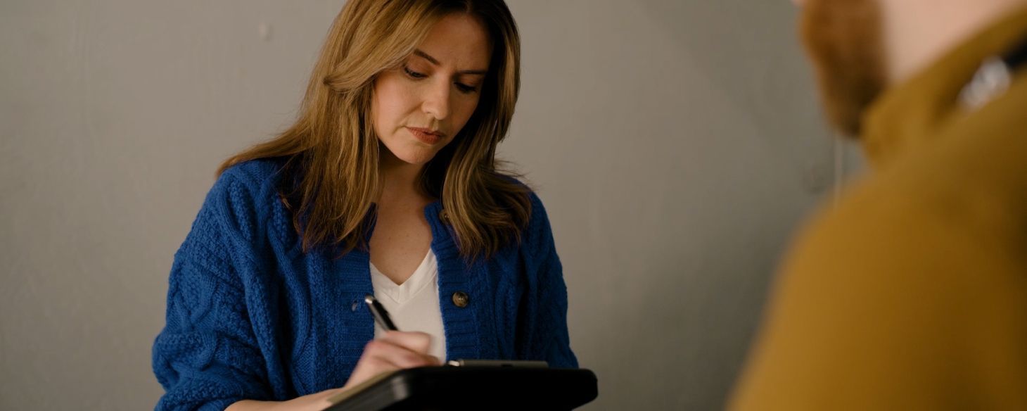 Woman signing paperwork on a clipboard while selling her car to Peddle