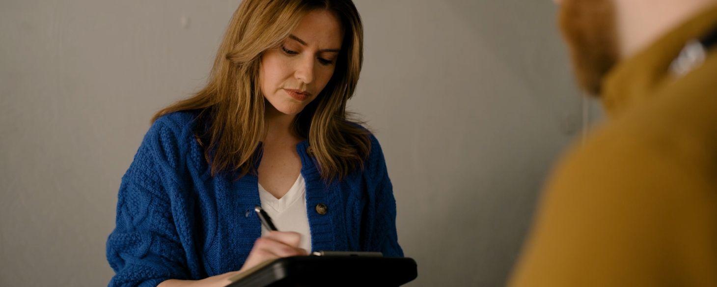 Woman signing paperwork on a clipboard while selling her car to Peddle