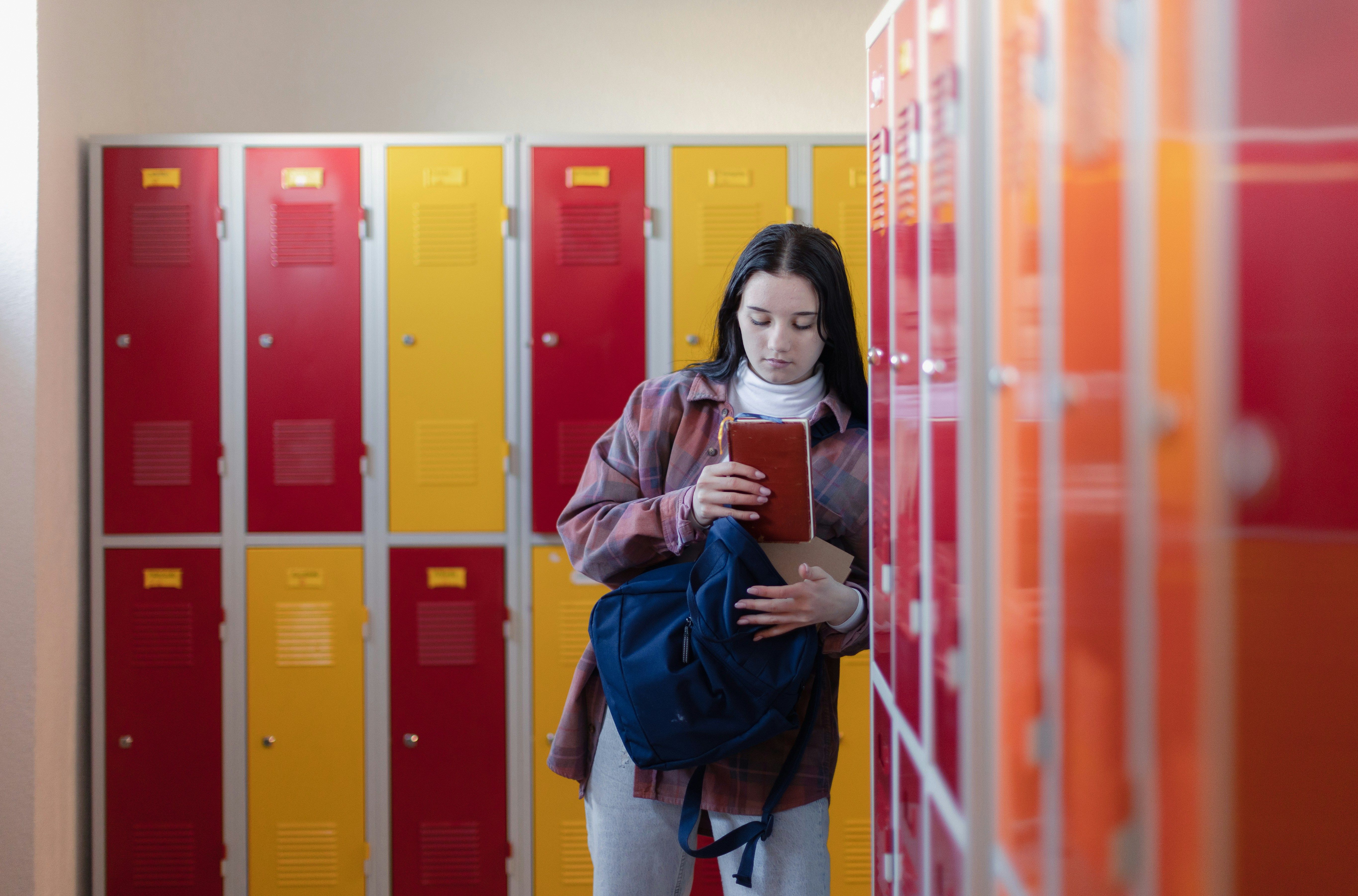 Student standing by lockers packing up her bookbag