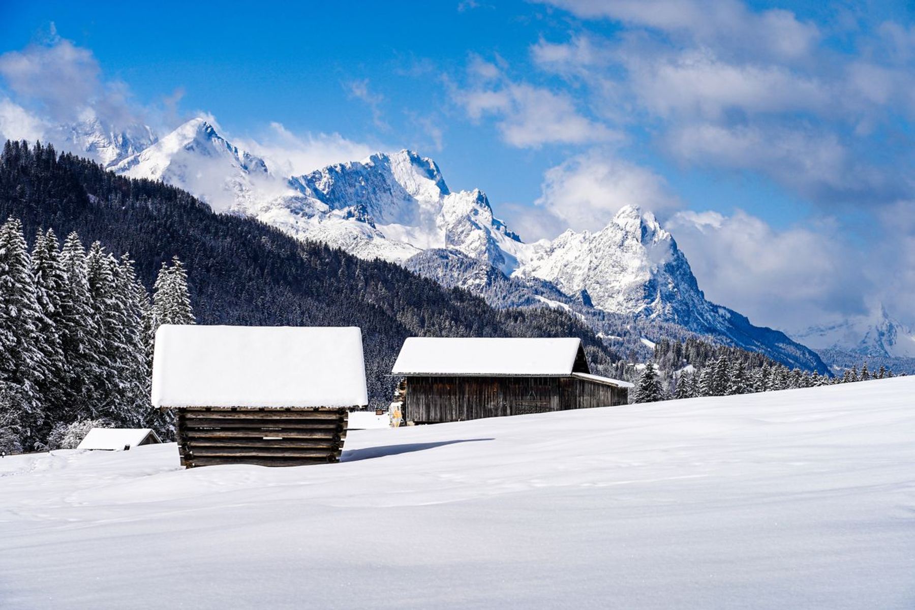 Snow-covered Alpine chalets beneath dramatic snow-capped mountain peaks