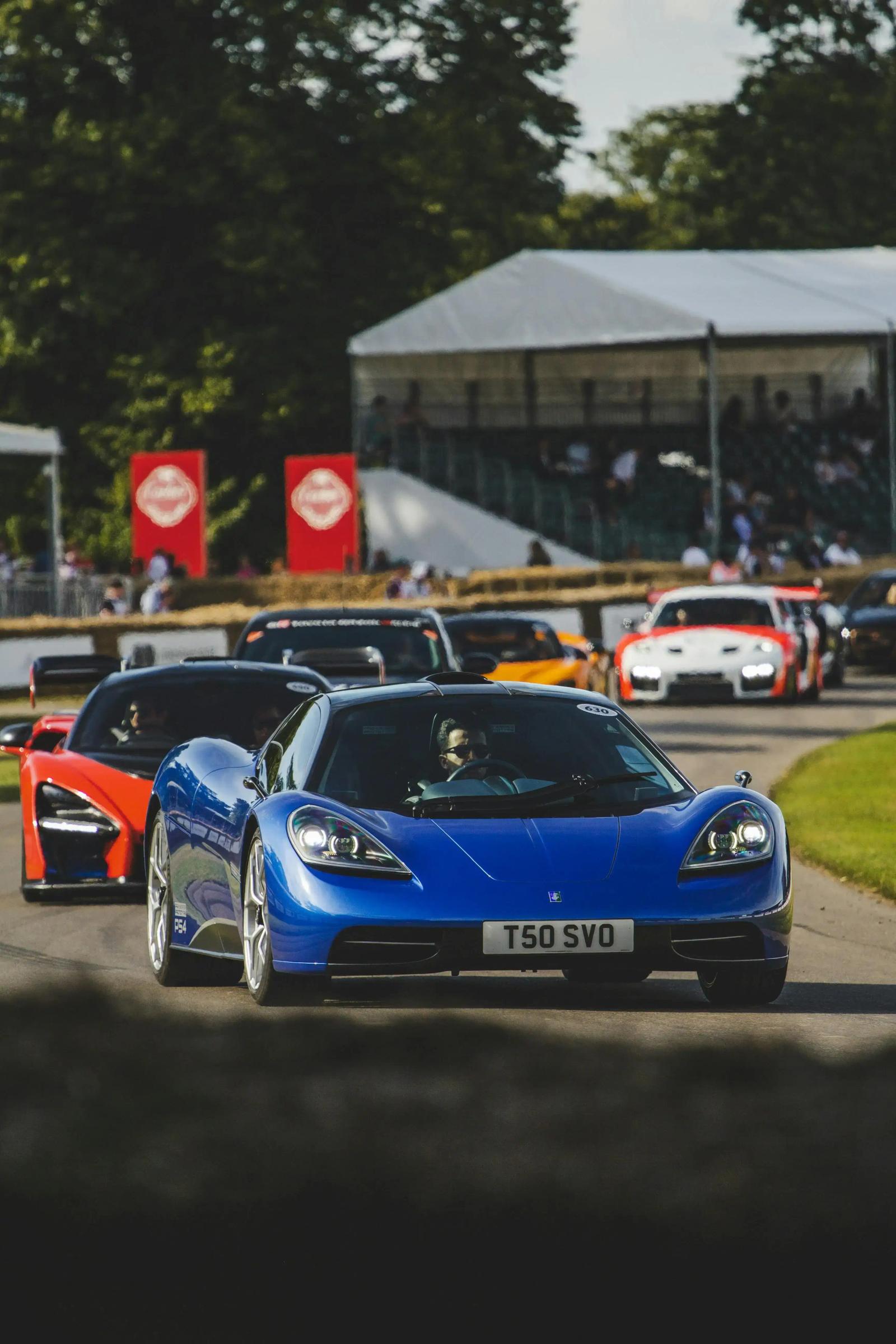 Supercars on the hillclimb circuit at Goodwood, featuring the blue T50 and red McLaren Senna.