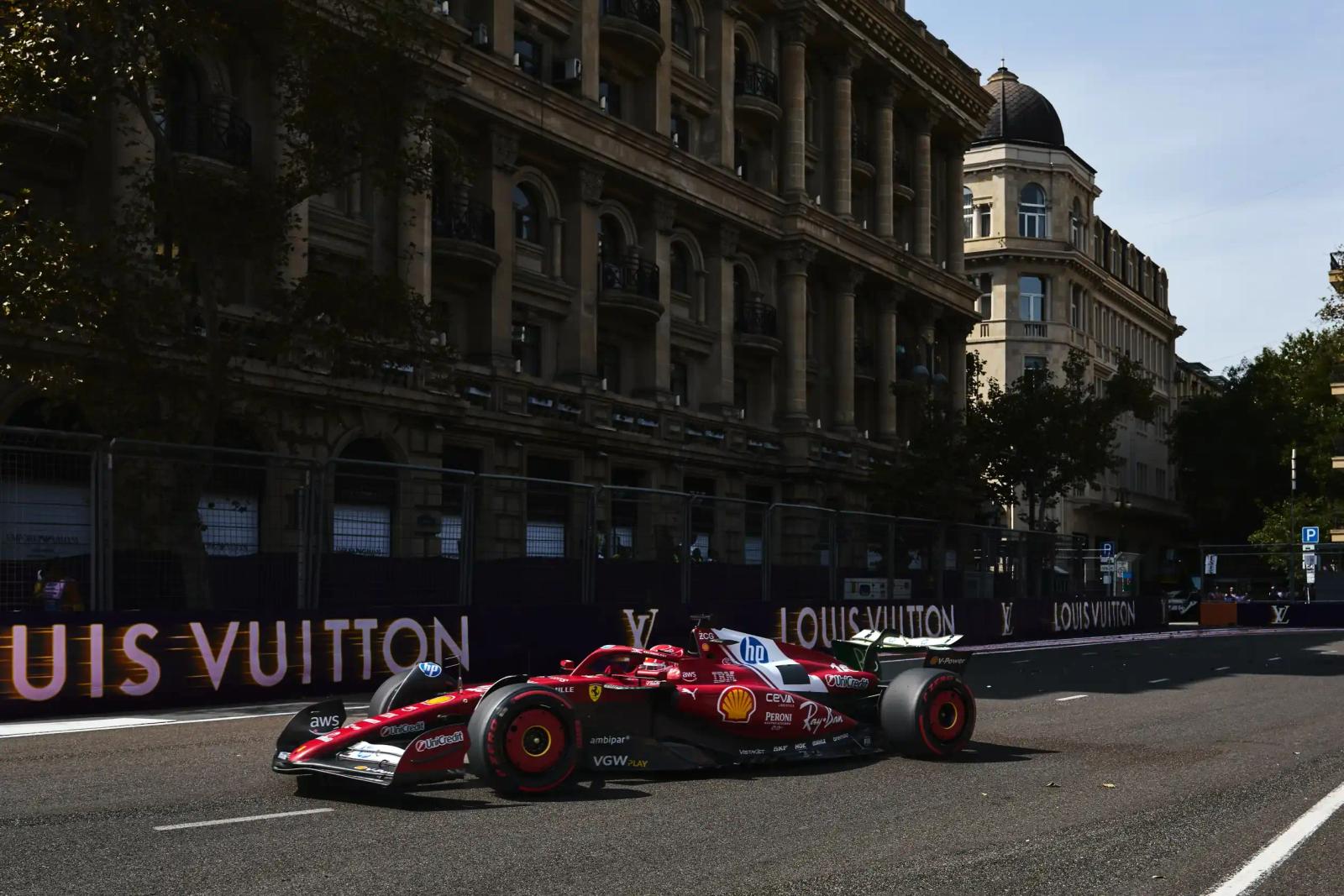 Scarlet Formula 1 car cornering on a city street circuit past grand stone facades.