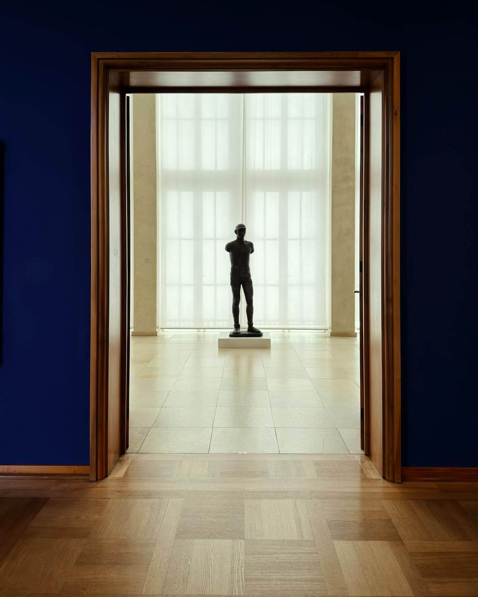 Minimalist art gallery interior with a central sculpture and high-contrast architectural lighting