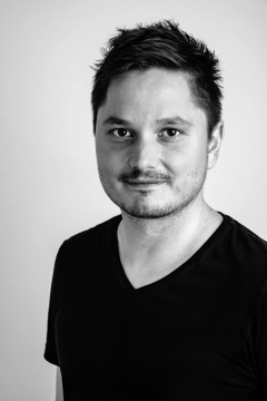 Black-and-white portrait of photographer David Szabo wearing a dark V-neck T-shirt.