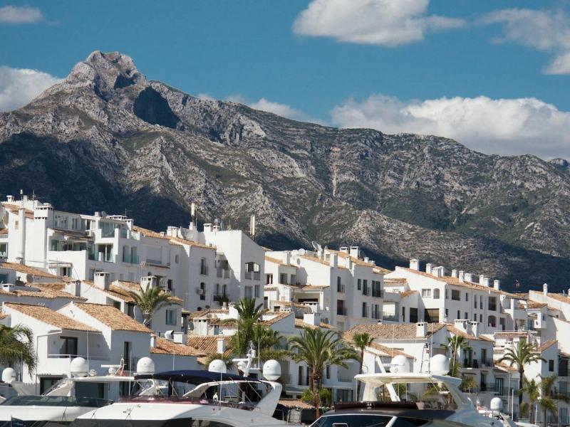 Luxury white yachts moored in a Spanish marina with whitewashed buildings and mountains behind