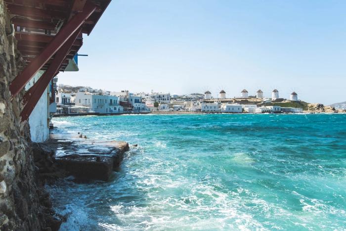 Rugged coastline of Mykonos featuring the iconic white windmills on the horizon