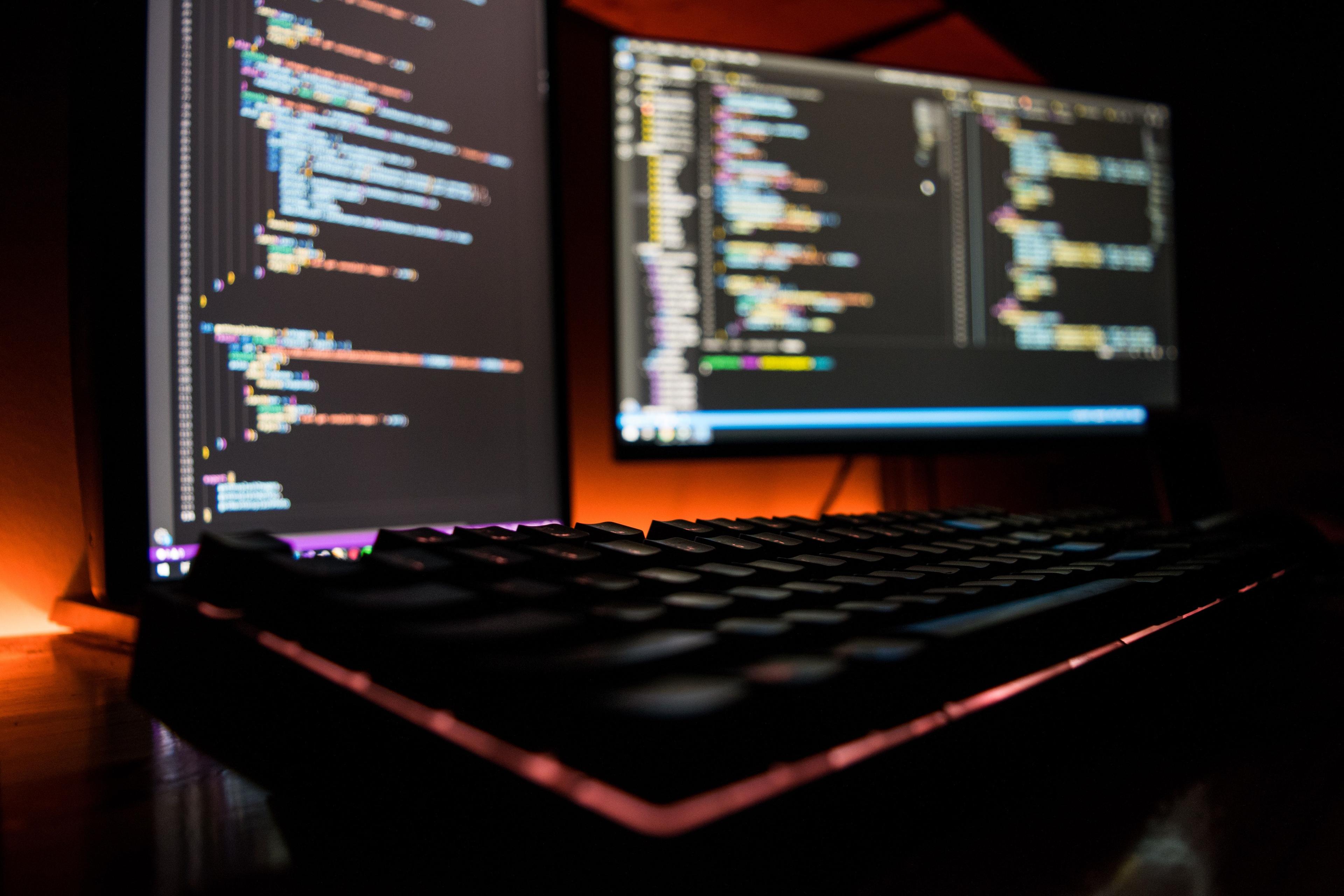 Desk showing computer set-up with visual studio code on the monitors