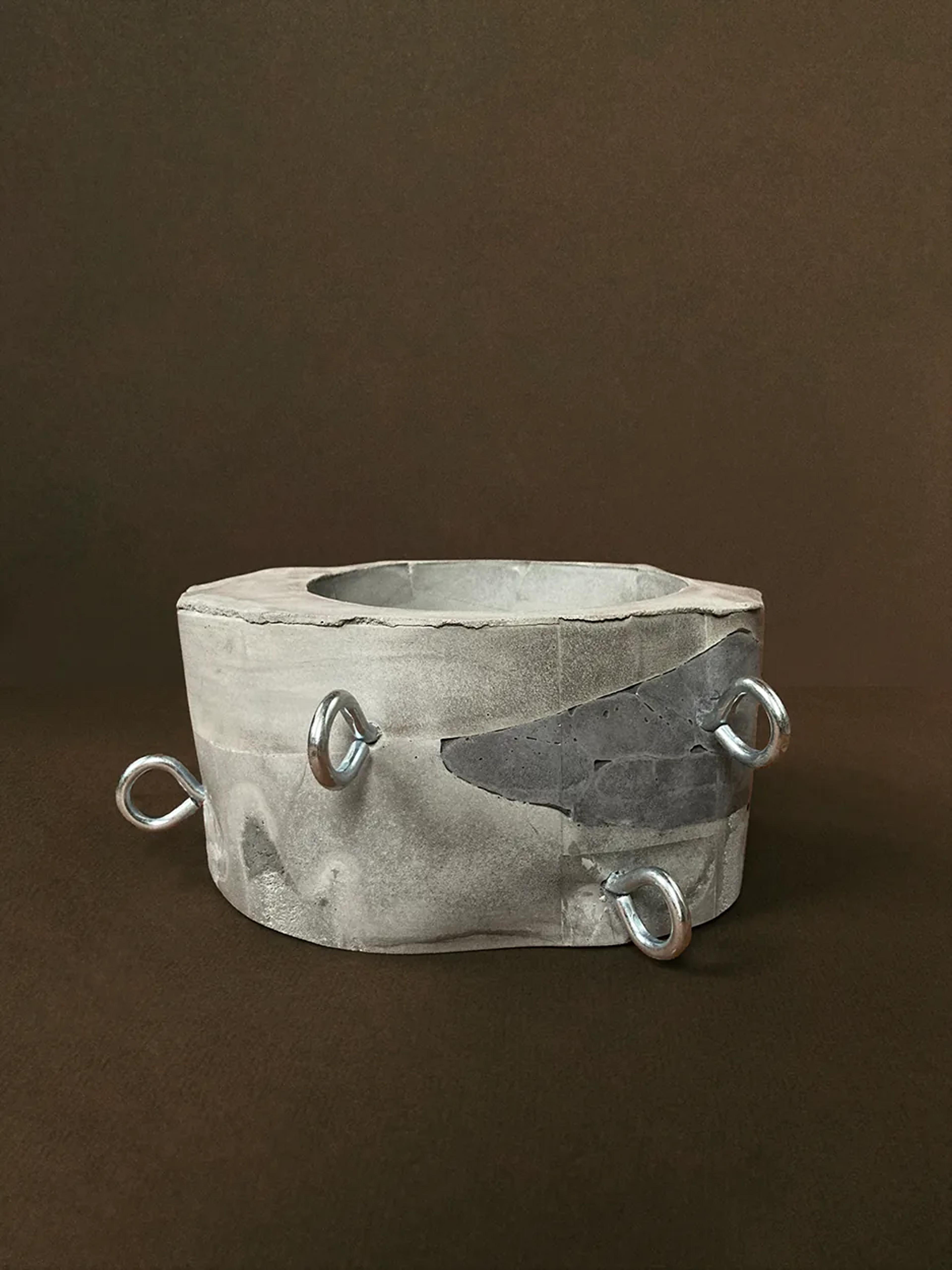 Run Your Finger Over My Hoops — a faceted concrete planter with three chrome rods, unplanted, view 1 of 3