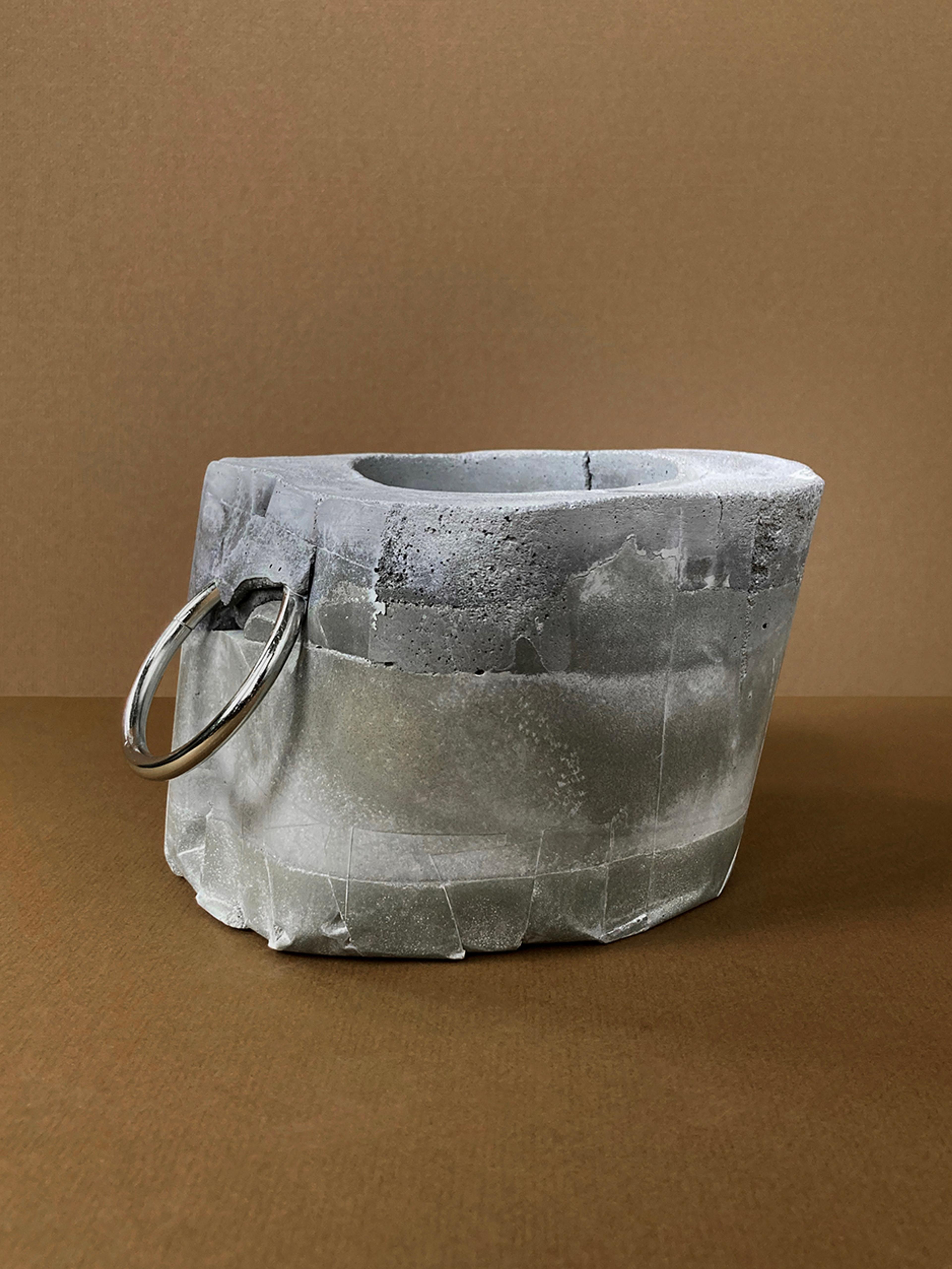 Kinky Planter #10 — a faceted concrete planter with a single ring, unplanted, side view, view 2 of 2
