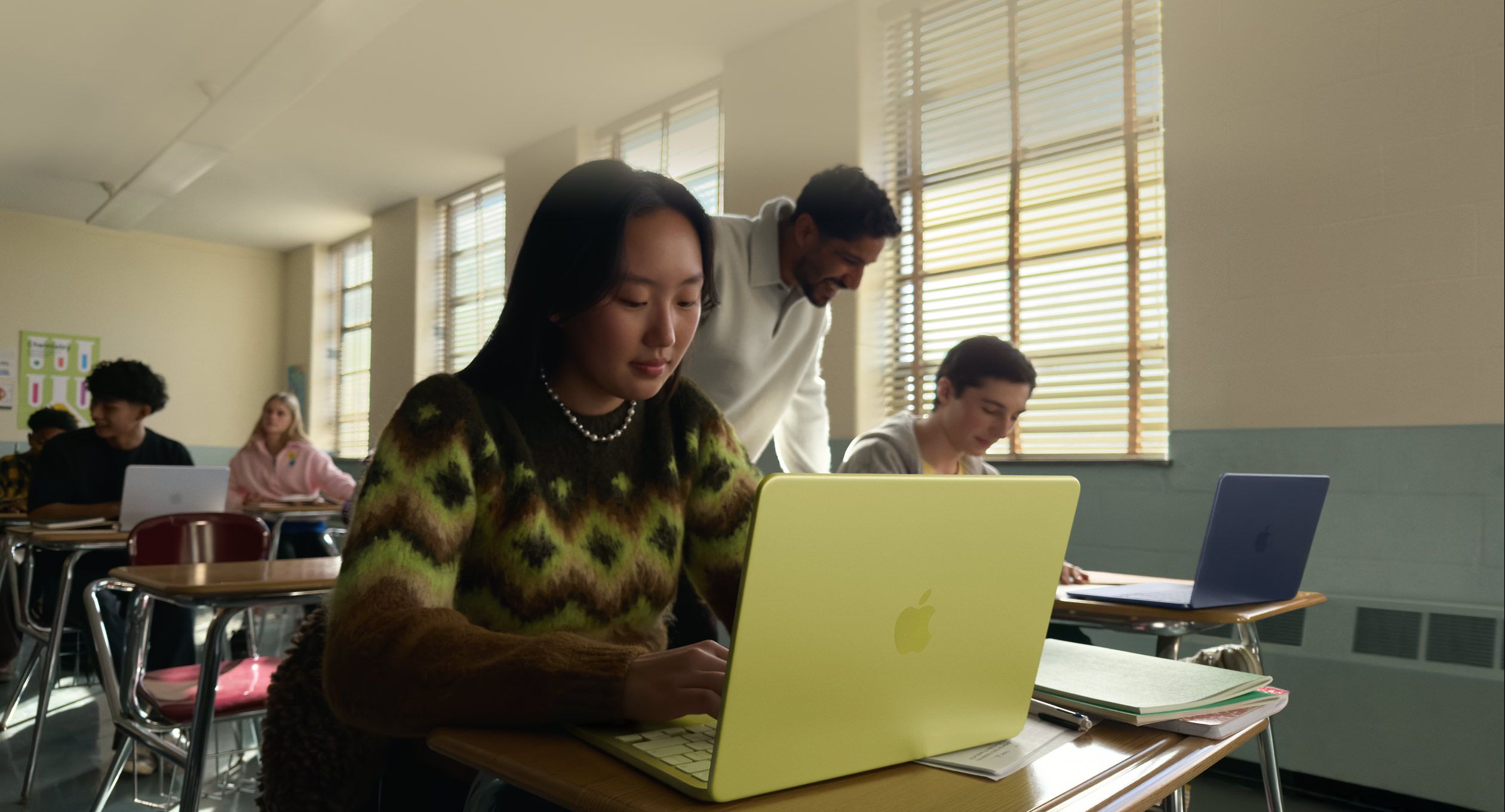 Une personne étudiant utilise un MacBook Neo, couleur jaune agrume, débranché, dans une salle de classe