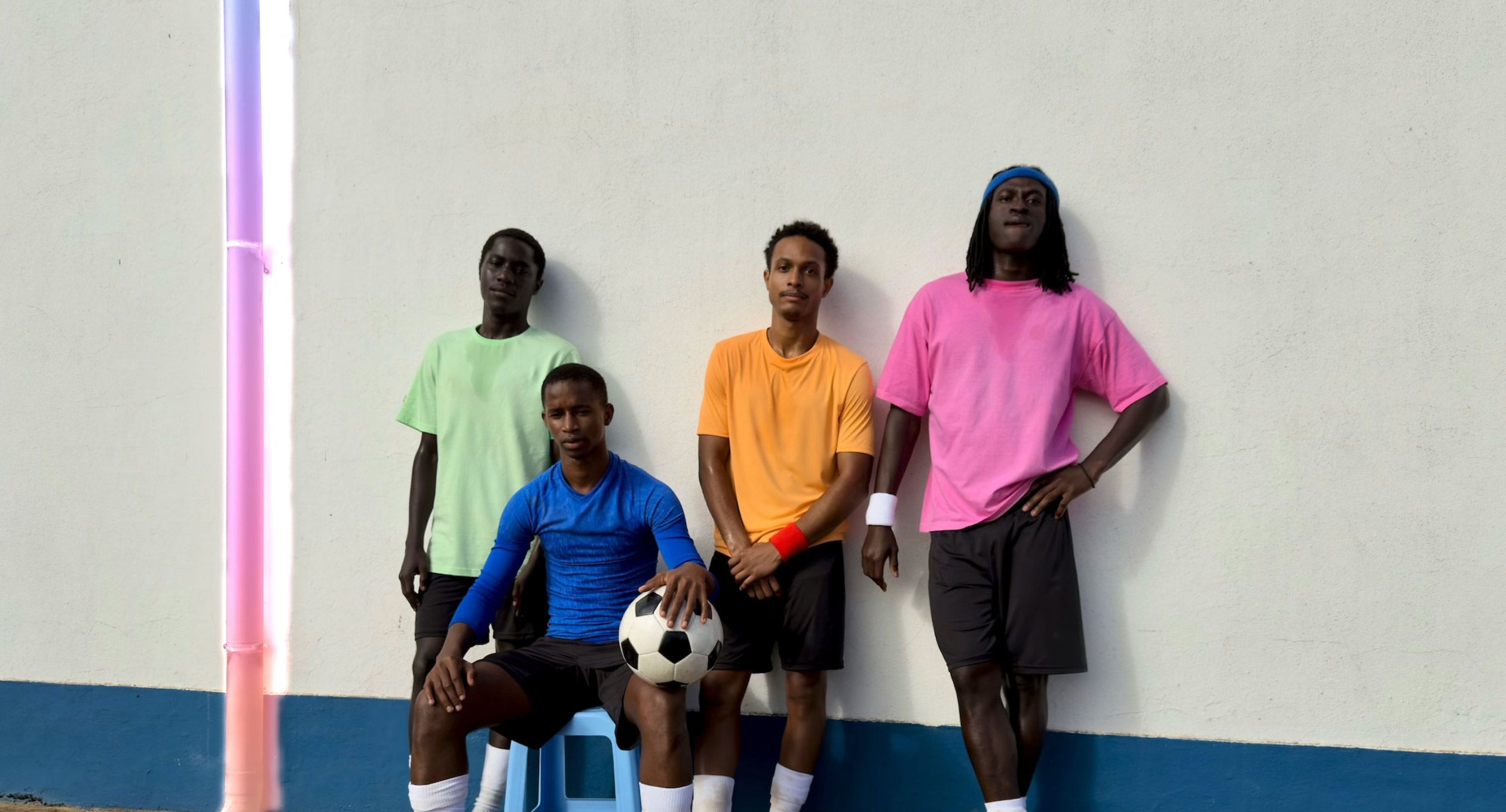 Utilisation de l’outil Correction pour supprimer une descente de gouttière d’une photo de joueurs de football posant contre un mur