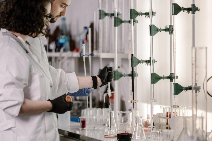Dos investigadores trabajando con pipetas y material de vidrio en una mesada de laboratorio