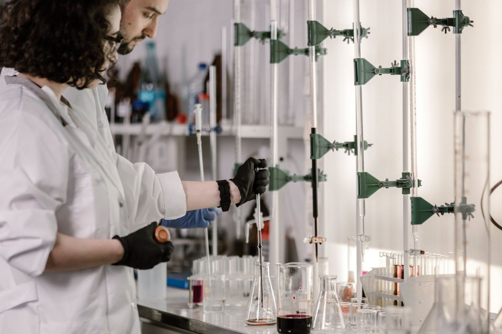 Dos investigadores trabajando con pipetas y material de vidrio en una mesada de laboratorio