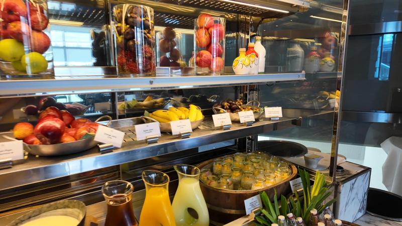 Bottles of juice and jugs on ice beside baskets of apples and bananas at the Bella Sera breakfast juice bar.