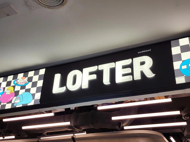 The illuminated LOFTER sign above the food court entrance with cartoon characters on a chequered panel.