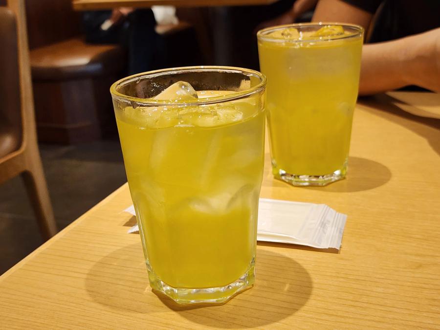 Two glasses of iced green tea on a wooden table at Tonkatsu Wako.