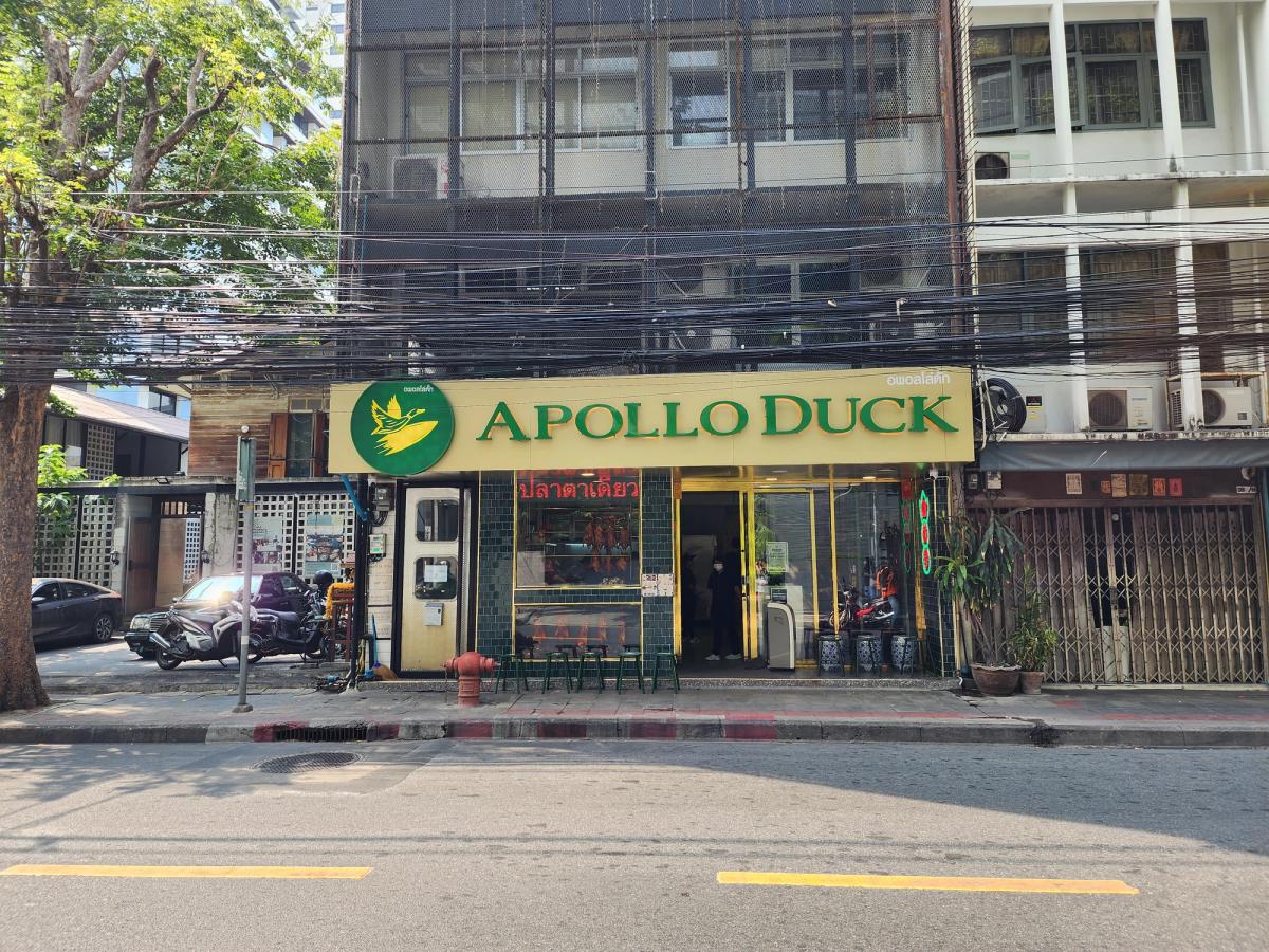 Front of the Apollo Duck restaurant in Bangkok with green and yellow signage and roast ducks hanging in the window.