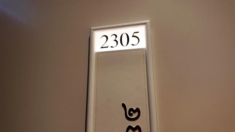 The lit room number plate for 2305 beside the door, with the number repeated in Thai numerals below.