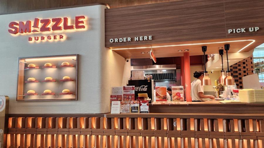 The Smizzle Burger counter at Open House with a lit sign and a display case of buns.