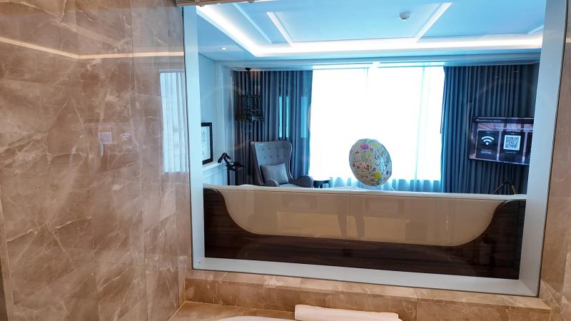 The bathtub at Sofitel Bangkok Sukhumvit set under a window that looks into the bedroom of Junior Suite 2305.
