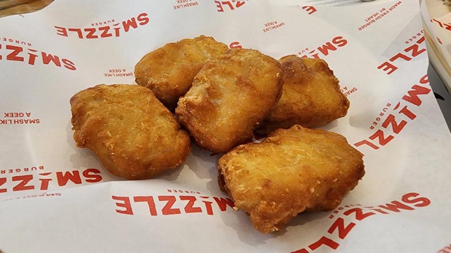 Five chicken nuggets on branded Smizzle paper.