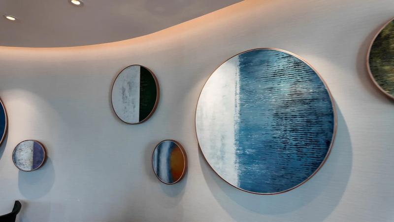 Round blue and white canvases of different sizes on a curved white wall in the Club Millésime lounge.