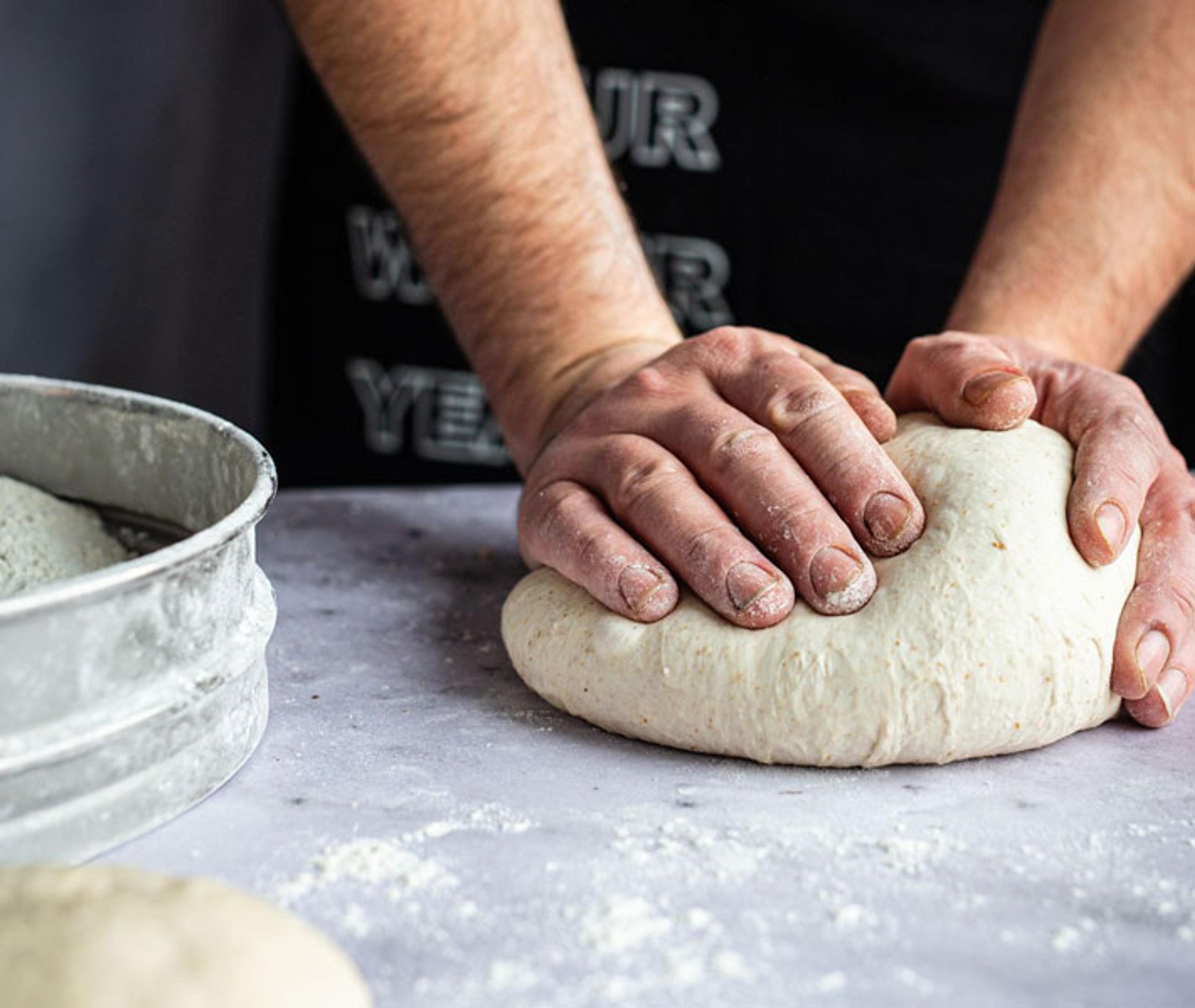Two hands kneading Base pizza dough