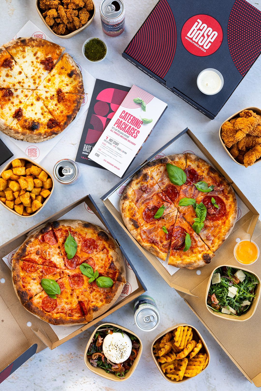 Base pizzas, sides and dips laid out for an office lunch