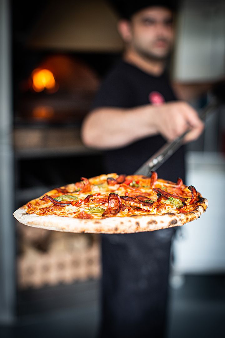 Pizza chef holding a freshly baked pizza on a peel