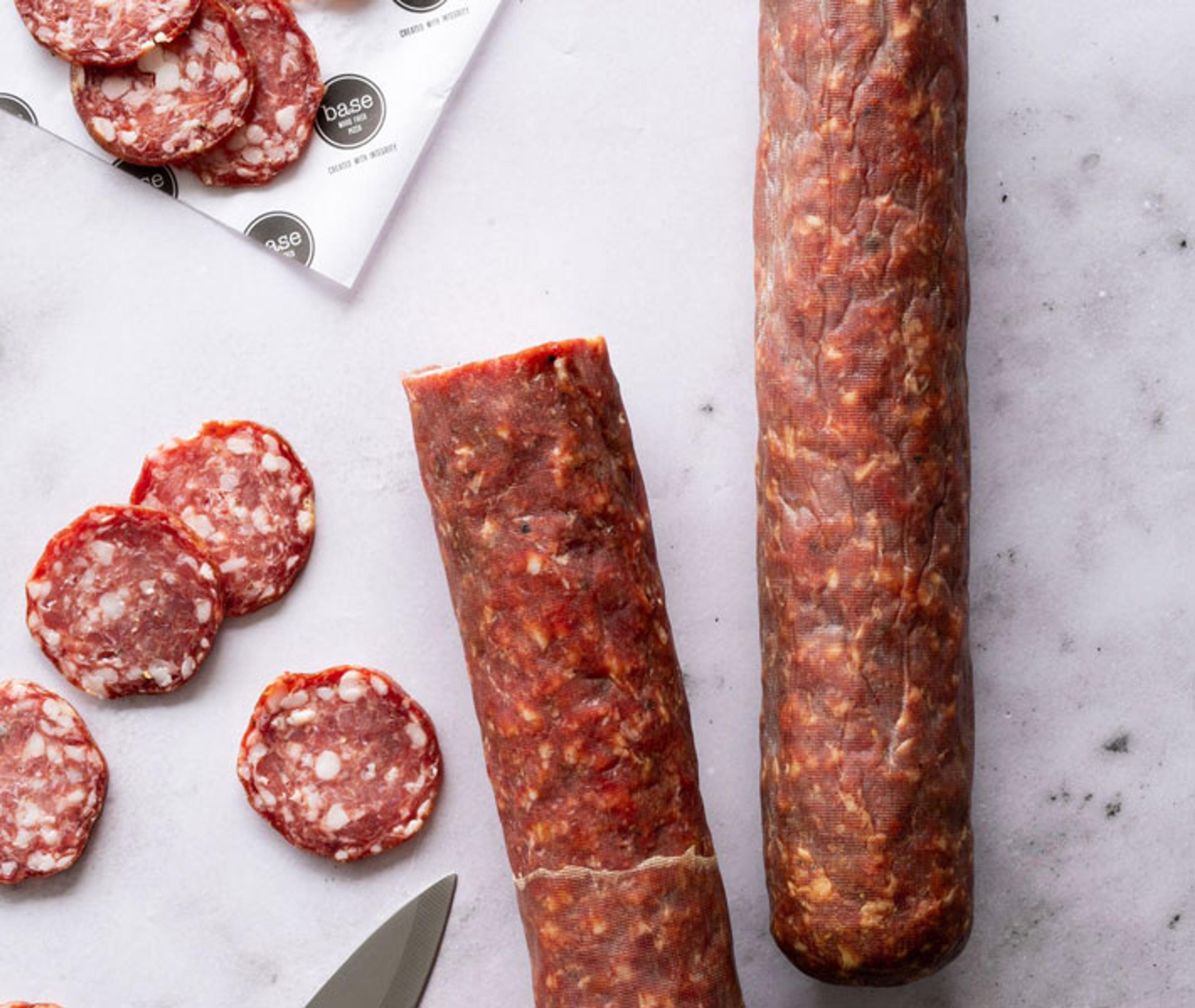 Sliced salami and whole cured sausages on marble