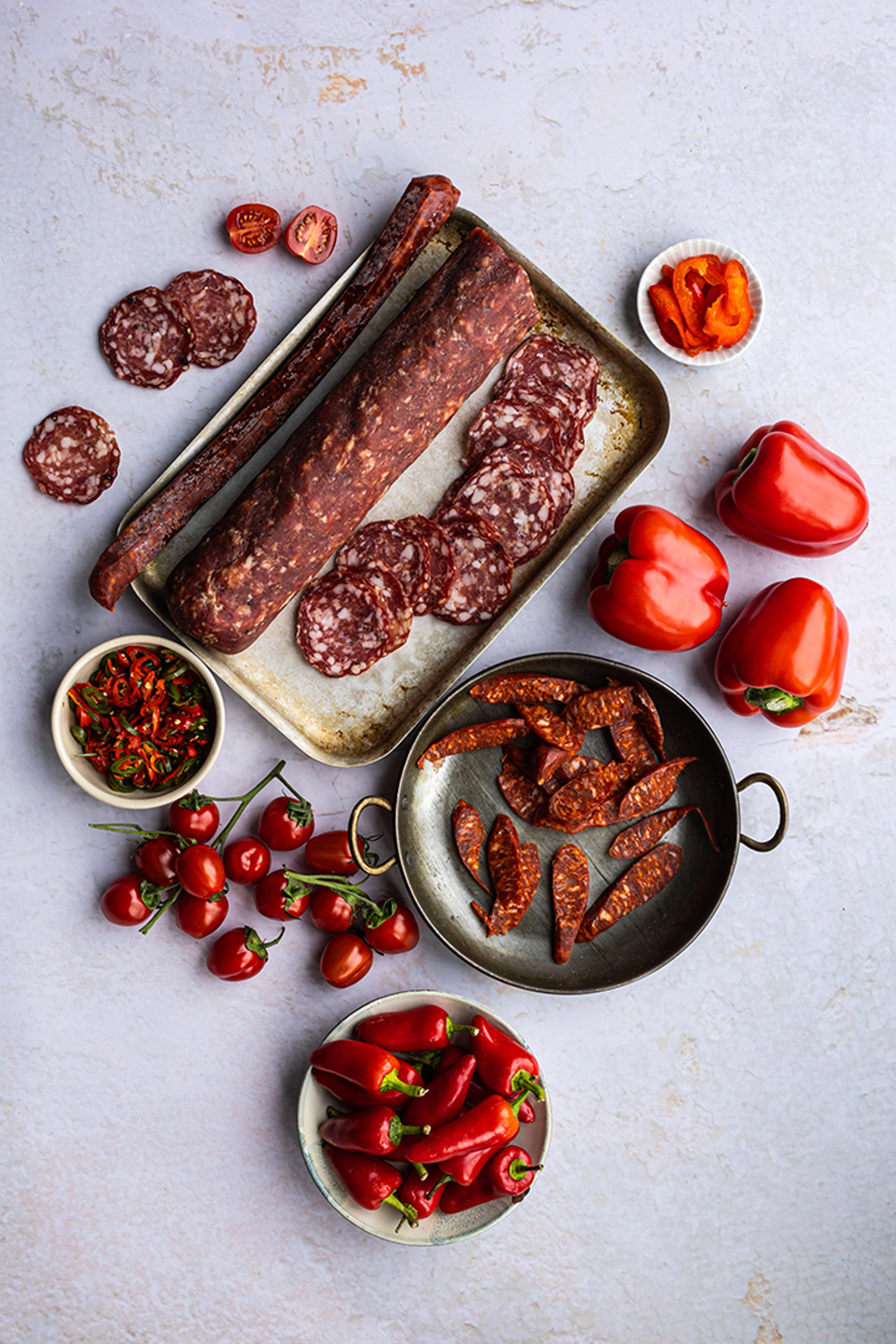 Charcuterie, chillies and cherry tomatoes laid out on marble