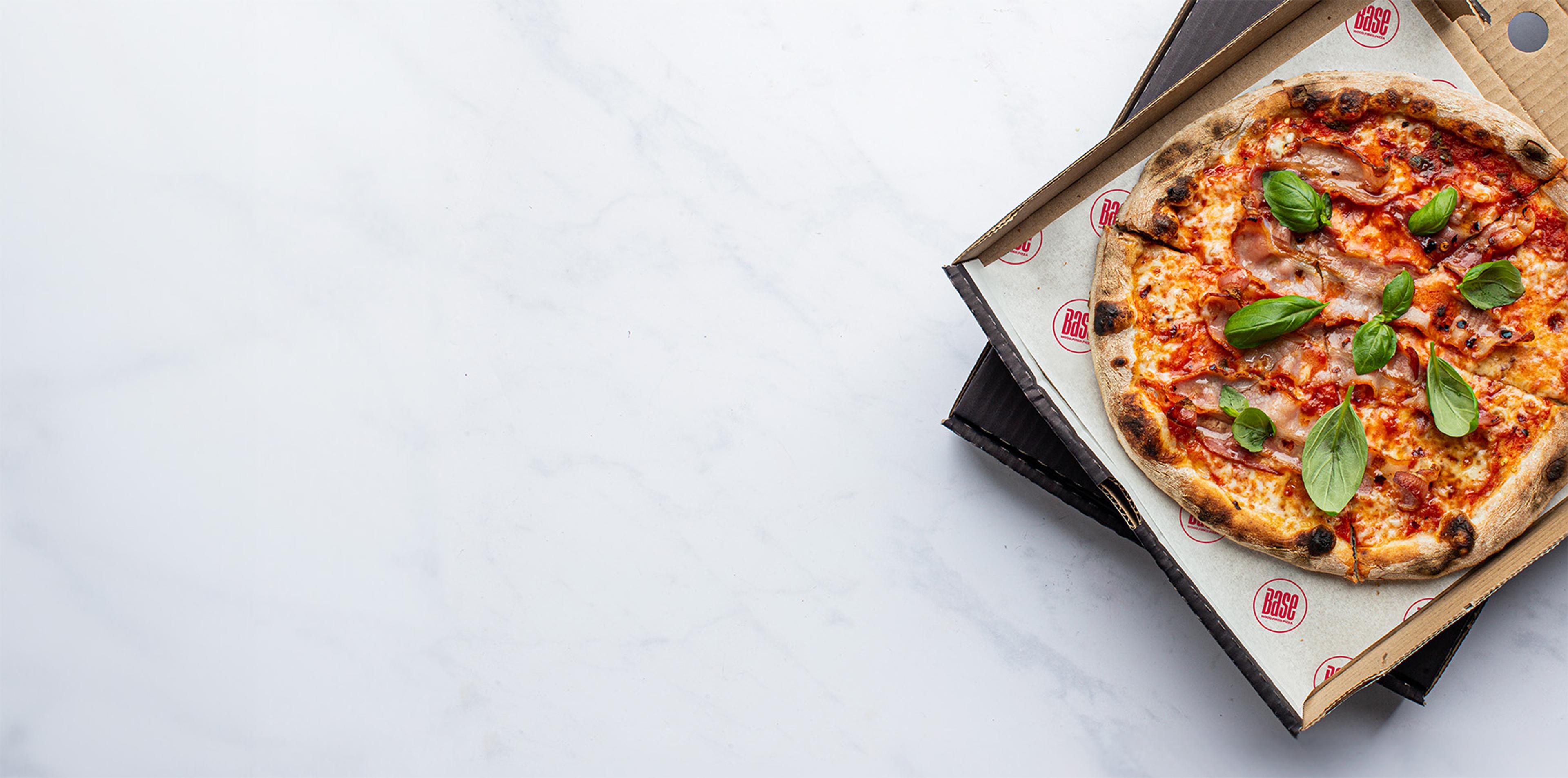 Base pizza in an open box on a marble counter