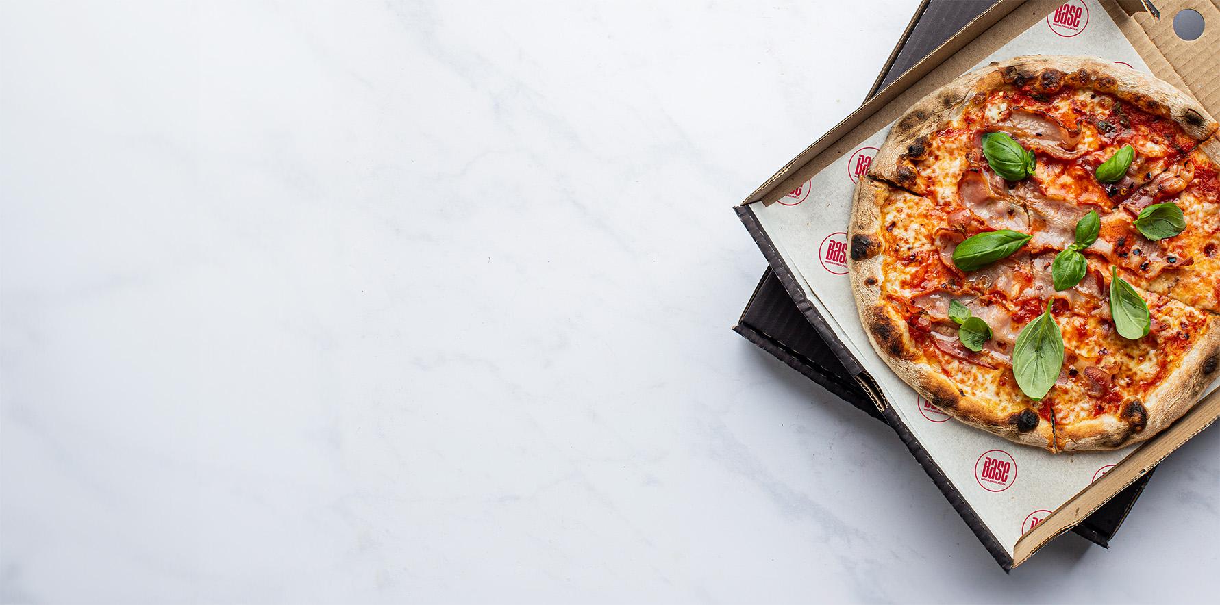 Base pizza in an open box on a marble counter