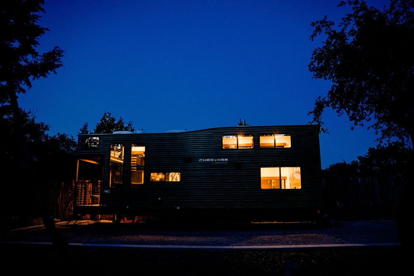 Wayside Wimberley glamping RV lit up at blue hour among the oaks