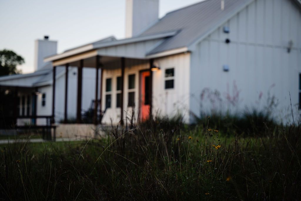 Yellow wildflowers blooming in front of a farmhouse cottage at Wayside Wimberley at dusk