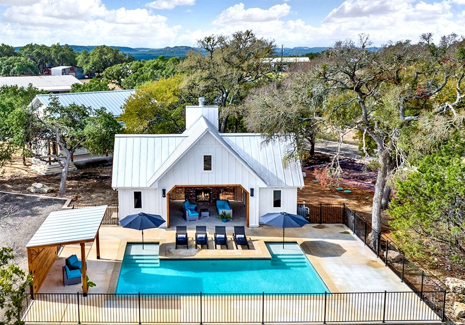 Aerial view of the pool, pavilion, and stone fireplace at Wayside Wimberley framed by Hill Country oaks