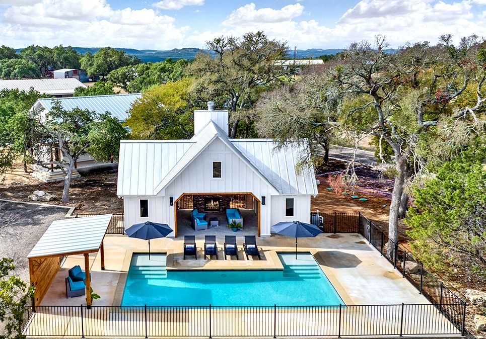 Aerial view of the pool, pavilion, and stone fireplace at Wayside Wimberley framed by Hill Country oaks