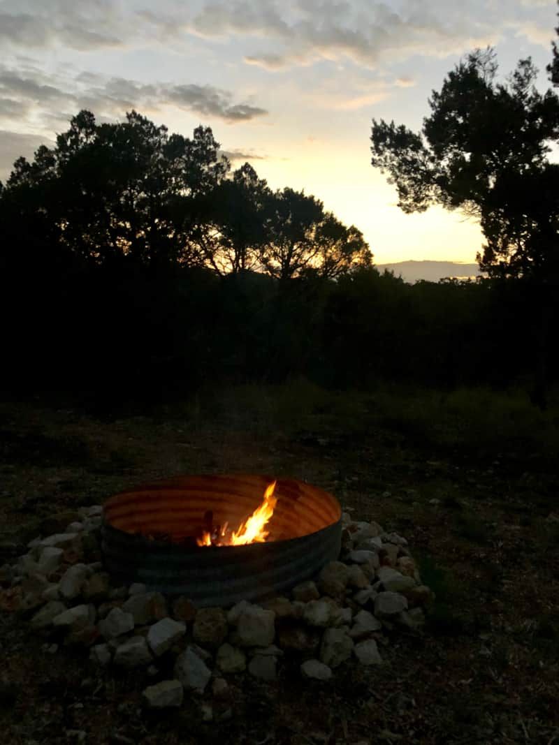 A fire burning in the shared fire pit at Wayside Wimberley against a Hill Country sunset