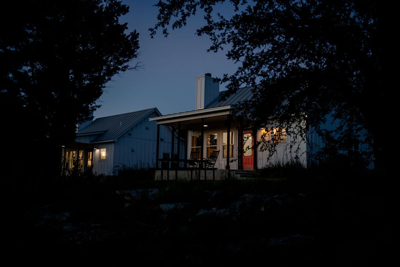 Wayside Wimberley cottages glowing at blue hour, seen through the oak trees