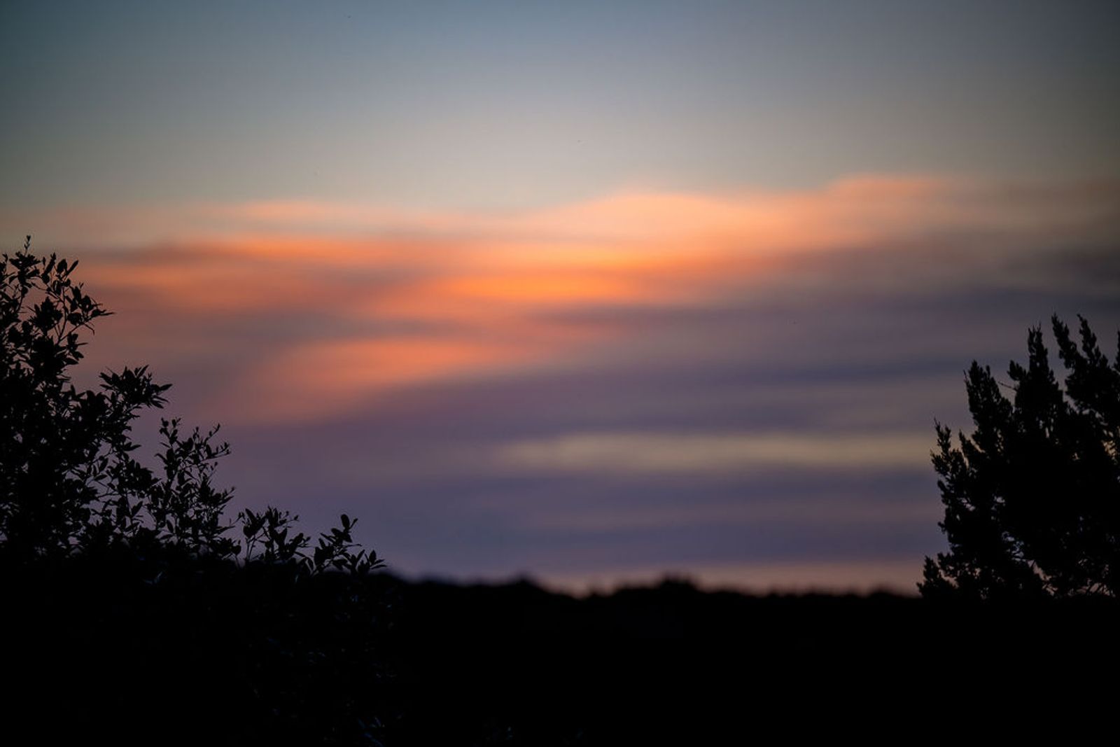 Orange and lavender sunset over the Hill Country tree line at Wayside Wimberley