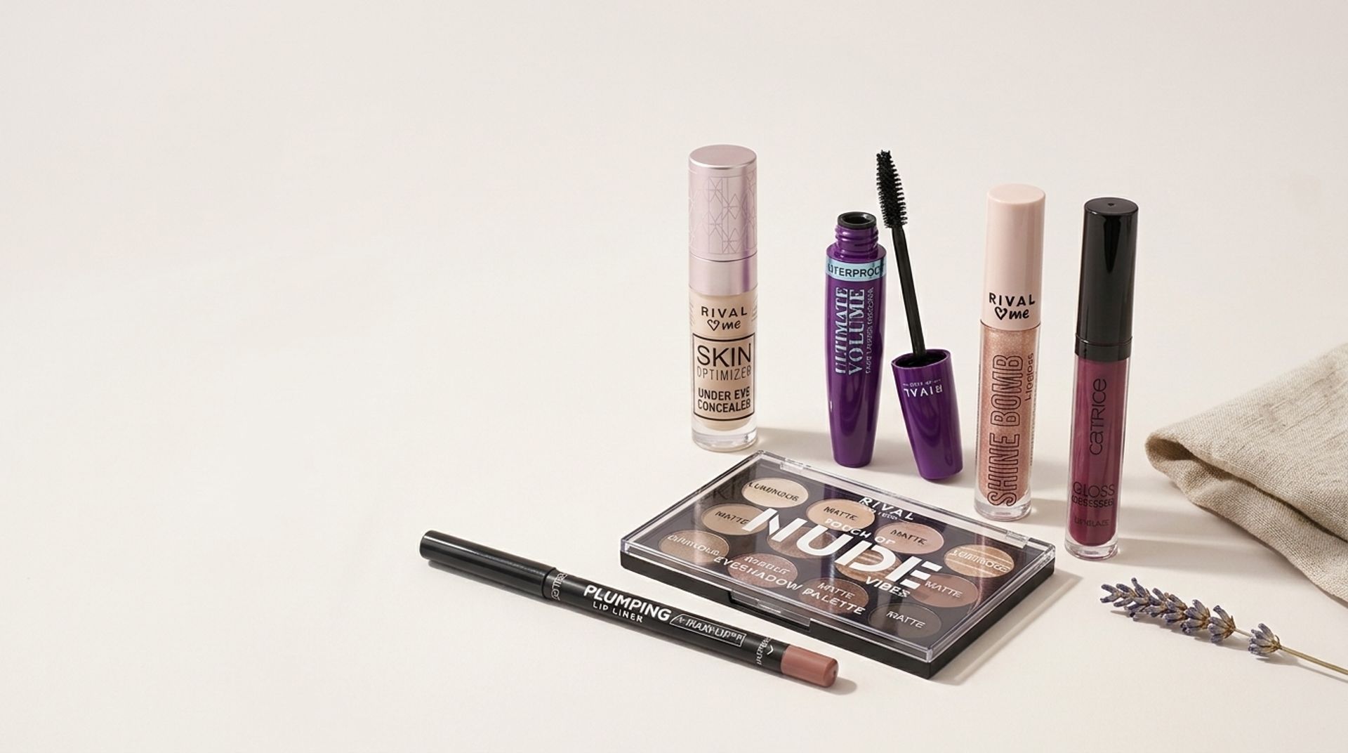 RIVAL loves me and Catrice makeup: concealer, mascara, lip gloss, eyeshadow palette and lip liner on a cream surface