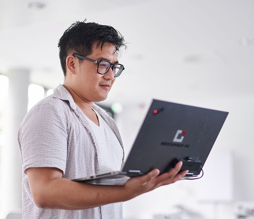 Person arbeitet mobil mit einem Laptop als Symbol für hybrides Arbeiten während einer Bachelor- oder Masterarbeit bei BROCKHAUS