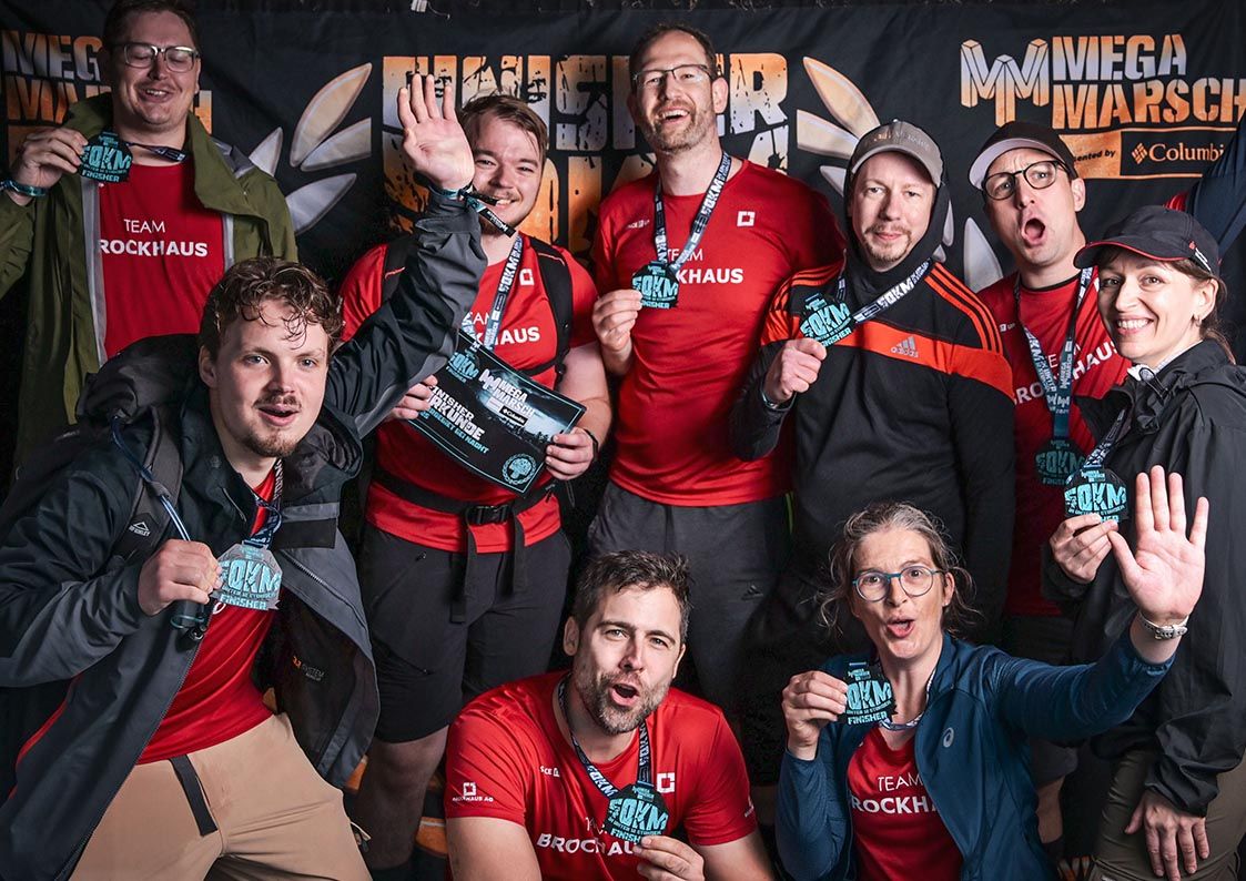 Gruppe von Teilnehmenden nach einem erfolgreichen Megamarsch mit Medaillen und Teamshirts.