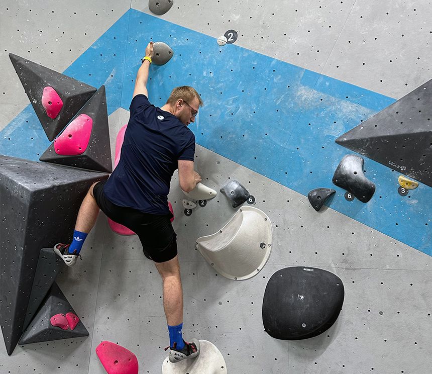 Person beim Bouldern an einer Kletterwand als Teil eines gemeinsamen Sportangebots.