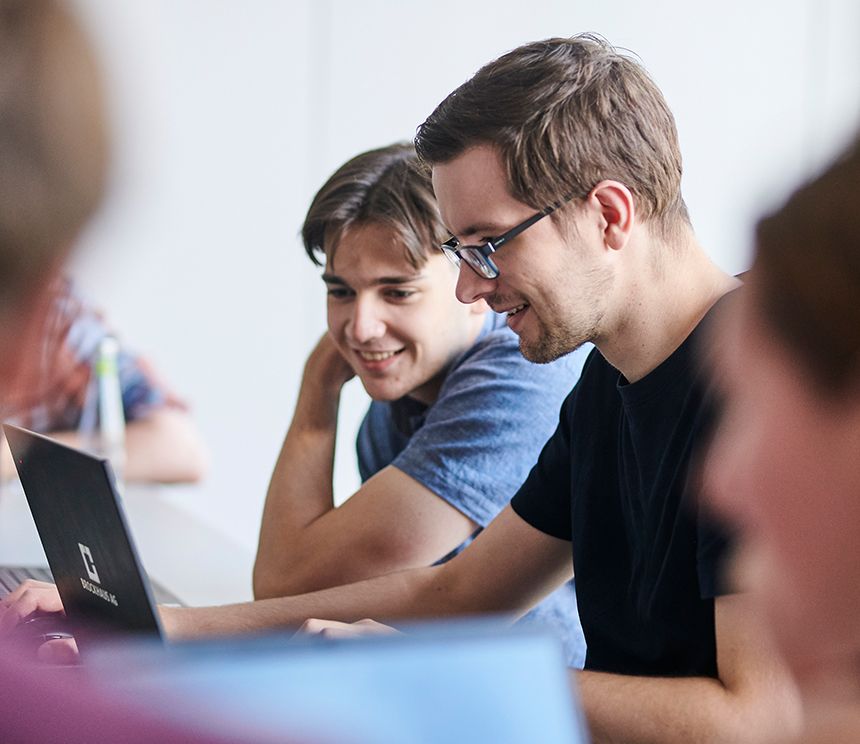 IT-Talents der BROCKHAUS AG arbeiten gemeinsam an einem Laptop im hybriden Arbeitsmodell