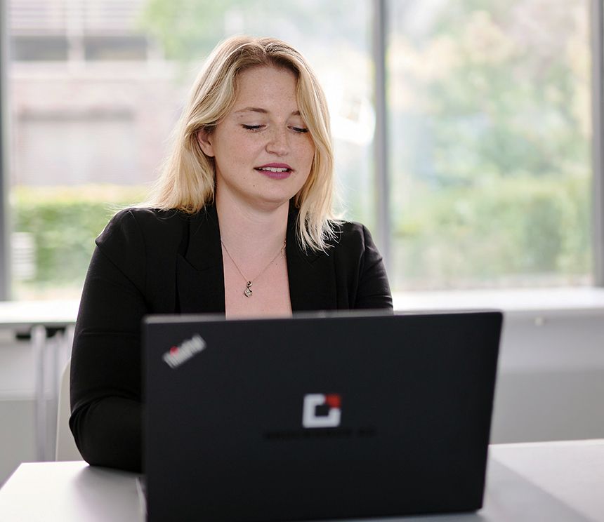 Werkstudentin arbeitet an einem Laptop im Rahmen eines hybriden Arbeitsmodells in der IT