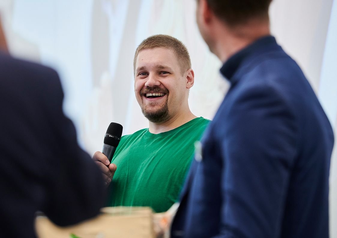 Person mit Mikrofon in einer Gesprächsrunde als Symbol für Kommunikation, Eigeninitiative und Teamgeist bei Werkstudierenden