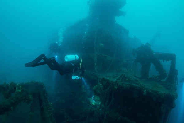 a scuba diver is swimming in the ocean near a shipwreck at seyðisfjörður in iceland.
