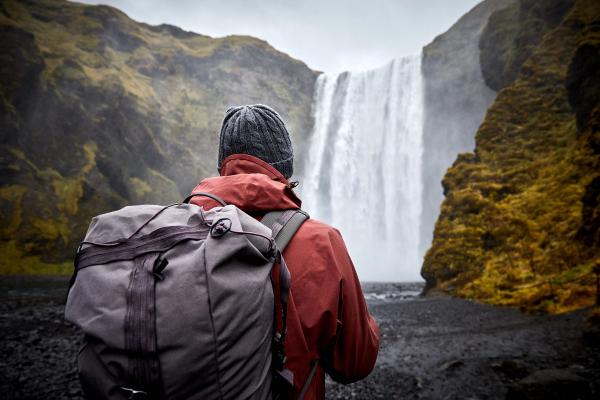 Hiker in Spring Hiker backpacker looking at Skogafoss Waterfall Southern Iceland during Spring